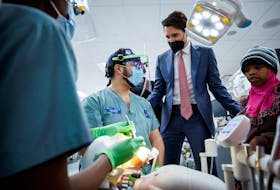 Canada's Prime Minister Justin Trudeau peers in as children learn about teeth from dental students during Trudeau's visit to the Schulich School of Medicine and Dentistry in London, Ontario, Canada, December 1, 2022. 