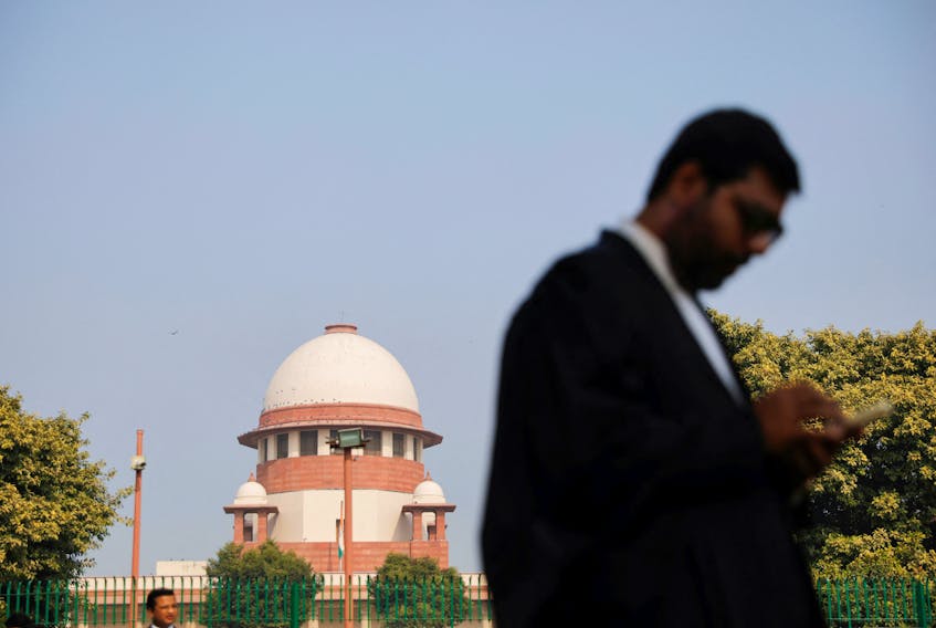 A lawyer looks into his mobile phone in front India's Supreme Court in New Delhi, December 11, 2023.