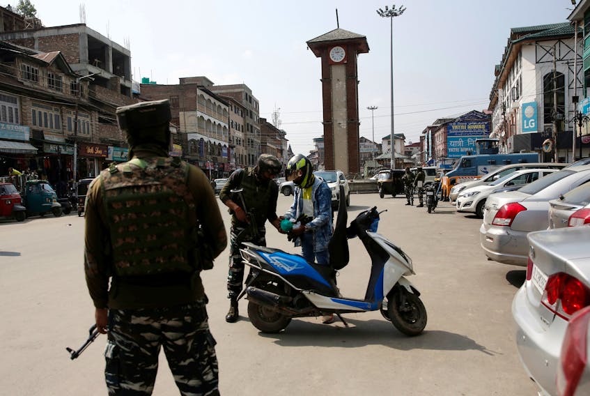 Indian Central Reserve Police Force (CRPF) personnel check the bags of a scooterist as part of security checking in Srinagar, October 12, 2021.