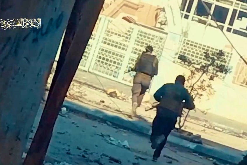 Hamas fighters run across the street at Rantissi hospital, amid the ongoing conflict between Israel and the Palestinian Islamist group Hamas, in Gaza City, in this screen grab taken from a handout video released on November 19, 2023. Hamas Military Wing/Handout via