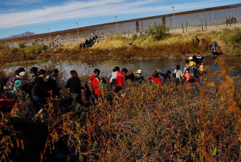 Migrants seeking asylum in the United States cross the Rio Bravo River, the border between the U.S. and Mexico, as seen from Ciudad Juarez, Mexico, December 5, 2023.