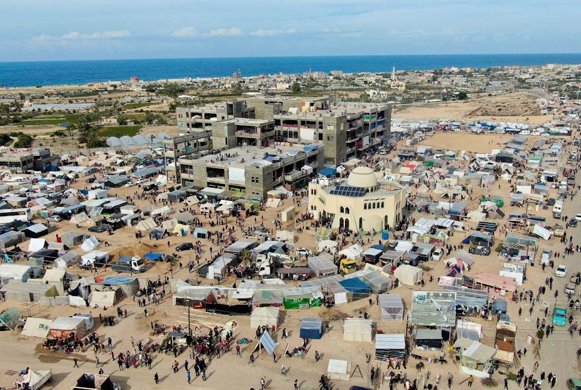 People walk near tent camps where displaced Palestinians, who fled their houses due to Israeli strikes amid the ongoing conflict between Israel and the Palestinian Islamist group Hamas, take shelter in Rafah in the southern Gaza Strip, December 9, 2023.