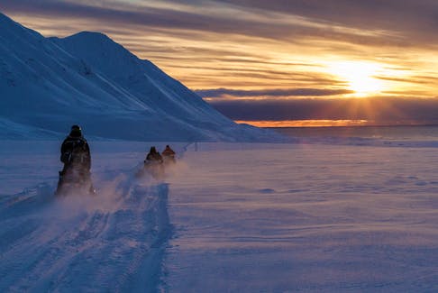 Scientists drive their snowmobiles cross the arctic towards Kongsfjord during sunset near Ny-Alesund, Svalbard, Norway, April 10, 2023.