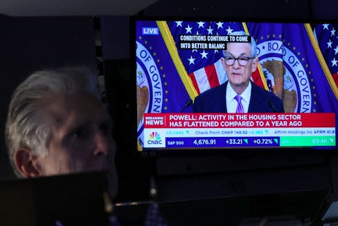 A trader works, as a screen displays a news conference by Federal Reserve Board Chairman Jerome Powell following the Fed rate announcement, on the floor of the New York Stock Exchange (NYSE) in New York City, U.S., December 13, 2023. 