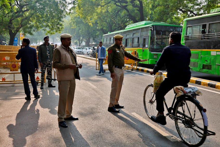A police officer stops a cyclist next to a barricade outside the parliament after a man jumped into the lawmakers' area of the lower house of India's parliament, in New Delhi, India, December 13, 2023.