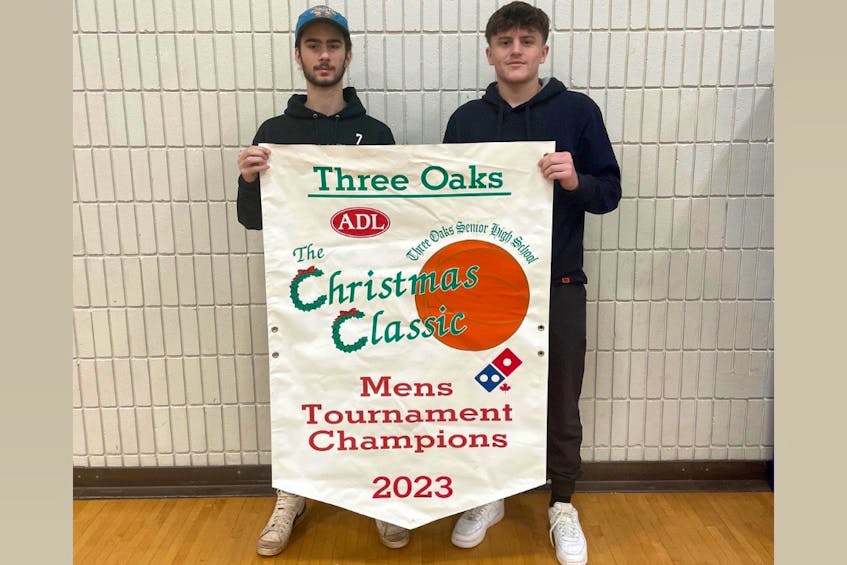 Seniors Quinn Harrington, left, and Faik Isufi with the host Three Oaks Axemen display the championship banner for the 30th edition of the Three Oaks Senior High School Christmas Classic senior AAA boys’ basketball tournament. The 12-team event runs at the Summerside high school on Dec. 15 and 16. - Joel Arsenault/Special to SaltWire