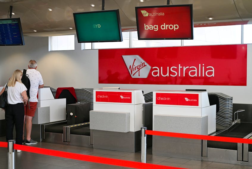 Travelers stand at a Virgin Australia Airlines counter at Kingsford Smith International Airport, in Sydney, Australia, March 18, 2020. 