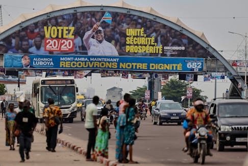 People wait for transport in front of a campaign poster of the Democratic Republic of Congo's President Felix Tshisekedi for the upcoming presidential elections, in Kinshasa, the Democratic Republic of Congo December 16, 2023.