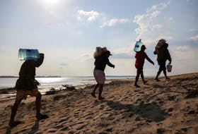 People from the Sao Francisco village carry water jugs they received as help during a historic drought in the Amazon near Paraua river in Careiro da Varzea, Amazonas state, Brazil October 26, 2023.