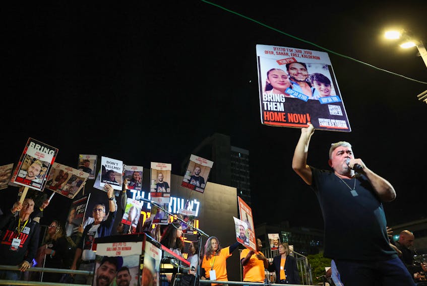 A man speaks on the microphone and holds up a sign as relatives and supporters of hostages kidnapped on the deadly October 7 attack by Palestinian Islamist group Hamas, rally for their release, after a temporary truce between Israel and the Palestinian Islamist group Hamas expired, in Tel Aviv, Israel, December 2, 2023.