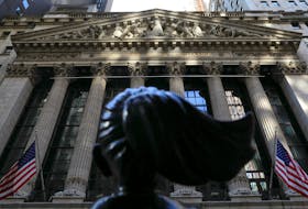 The back of the the "Fearless Girl" statue is pictured as morning sunlight falls on the facade of the New York Stock Exchange (NYSE) building after the start of Thursday's trading session in Manhattan in New York City, New York, U.S., January 28, 2021.
