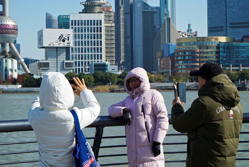 People wearing down jackets take pictures on the Bund on a cold winter day in Shanghai, China December 21, 2023.