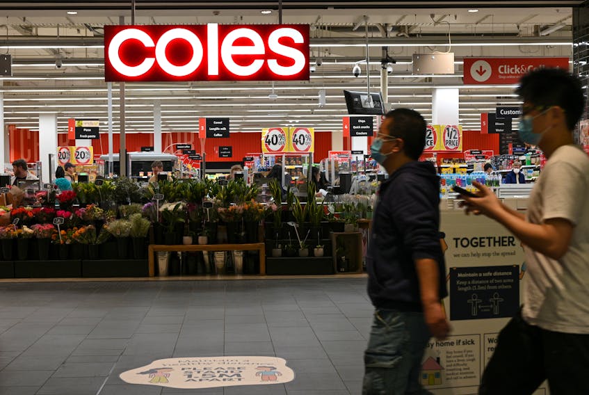 People in protective face masks walk past a Coles supermarket following the easing of restrictions implemented to curb the spread of the coronavirus disease (COVID-19) in Sydney, Australia, June 17, 2020. 