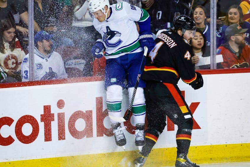  Calgary Flames defenceman Rasmus Andersson checks Vancouver Canucks forward Sam Lafferty at the Scotiabank Saddledome in Calgary on Saturday, Dec. 2, 2023.