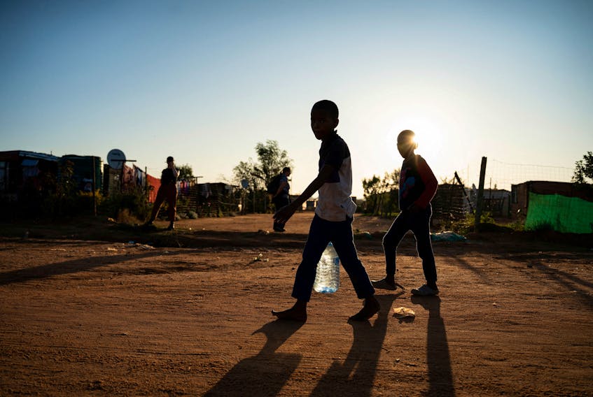 Young residents carry water home after filling up a bottle at a community filling station in the informal settlement of Kanana after individuals died from cholera in Hammanskraal, South Africa, May 24, 2023. 