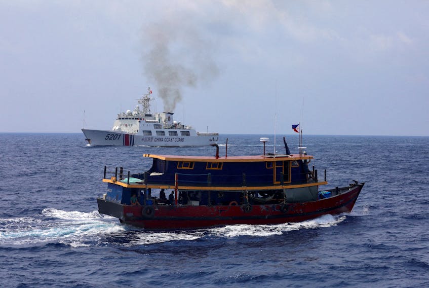A Philippine supply boat sails near a Chinese Coast Guard ship during a resupply mission for Filipino troops stationed at a grounded warship in the South China Sea, October 4, 2023.