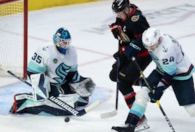 Seattle Kraken defenceman Jamie Oleksiak ties up Ottawa Senators left wing Brady Tkachuk as goaltender Joey Daccord makes a save.