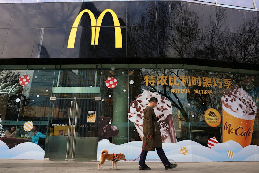 A man walks a dog past a McDonald's restaurant in Beijing, China December 4, 2023.