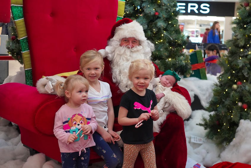 Everly McGuigan, left, Lexie McGuigan, Lucy McGuigan and Maeve McGuigan pose for a photo with Santa Claus at the Royalty Crossing mall on Dec. 2. Vivian Ulinwa • The Guardian