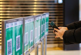 A person scans a QR code as QR codes for the "LeaveHomeSafe" COVID-19 contact-tracing app are seen outside a shopping mall at the first day of a vaccine passport roll out, following the coronavirus disease (COVID-19) outbreak, in Hong Kong, China, February 24, 2022.