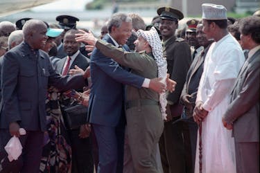 Nelson Mandela (L) is embraced by PLO leader Yasser Arafat as he arrives at Lusaka airport February 27, 1990. 