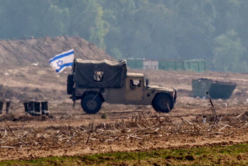 An Israeli flag flies on a military vehicle as the Israeli army operates at the border with Gaza, amid the ongoing conflict between Israel and the Palestinian Islamist group Hamas, as seen from southern Israel, December 5, 2023.