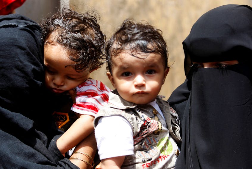 Women hold their children as they wait outside a health center where they will receive nutritional support from the World Food Programme (WFP) in the north-western Yemeni city of Hajja June 9, 2010.  Picture taken June 9, 2010. 