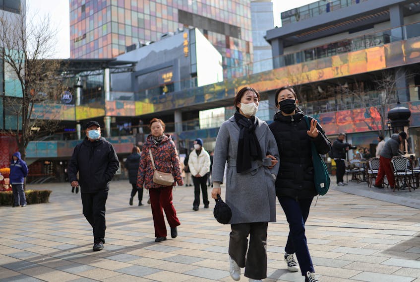 People walk at a shopping compound in Beijing, China December 6, 2023.