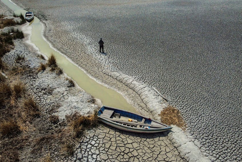 Manuel Flores walks on a dry area that shows the drop in the level of Lake Titicaca, Latin America's largest freshwater basin, as it is edging towards record low levels, on Cojata Island, Bolivia October 26, 2023.      