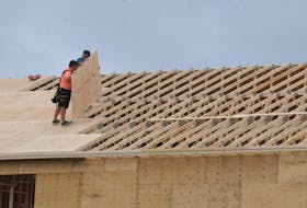Construction workers affix 4’x8’ pieces of plywood to the roof trusses of a new house being built in Paradise on Friday morning, Aug. 12. Joe Gibbons • The Telegram