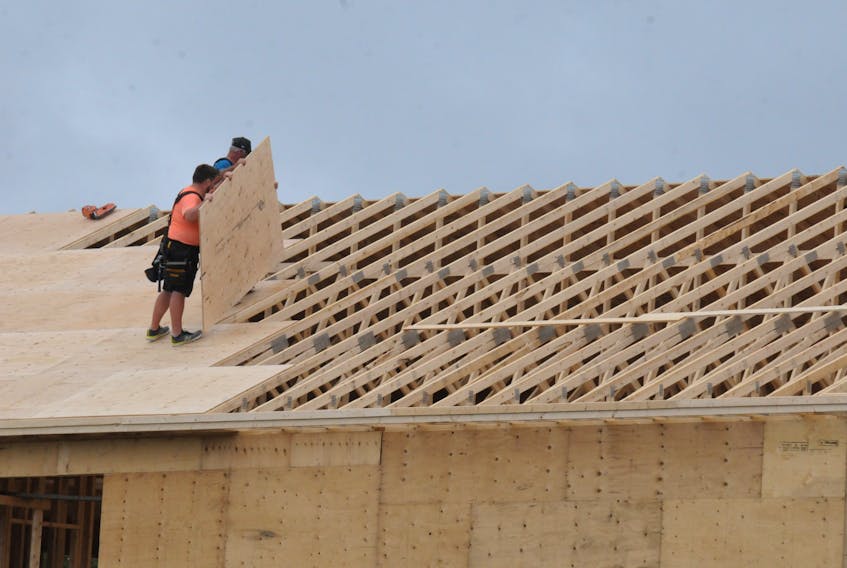 Construction workers affix 4’x8’ pieces of plywood to the roof trusses of a new house being built in Paradise on Friday morning, Aug. 12. Joe Gibbons • The Telegram