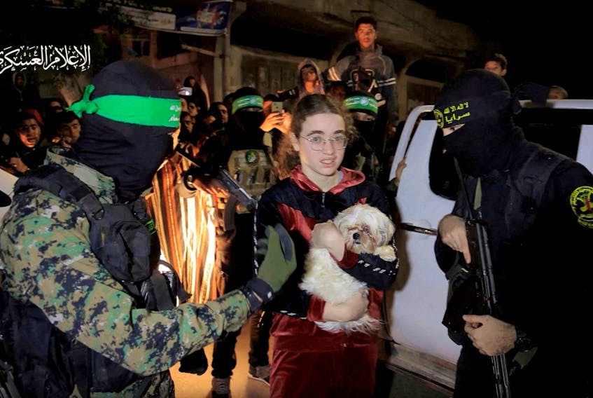Mia Leimberg, a hostage who was abducted by Hamas gunmen during the October 7 attack on Israel, holds her dog Bella while she and others are handed over by Hamas militants to members of the International Committee of the Red Cross, as part of a hostages-prisoners swap deal between Hamas and Israel amid a temporary truce, in an unknown location in the Gaza Strip, in this screengrab taken from video released November 28, 2023. Hamas Military Wing/Handout via