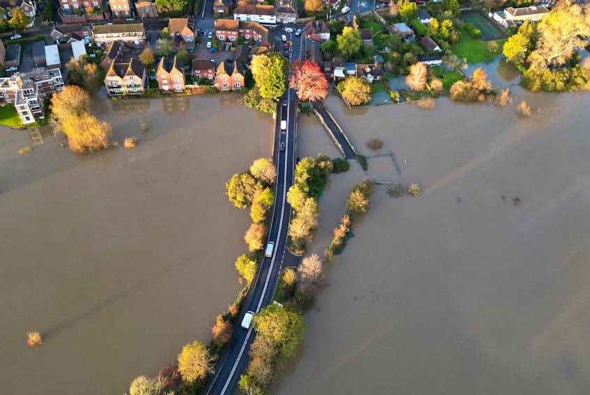 Cars drive along a road surrounded by floodwater after the River Arun burst its banks in the aftermath of Storm Ciaran, in Pulborough, Sussex, southern Britain, November 3, 2023.