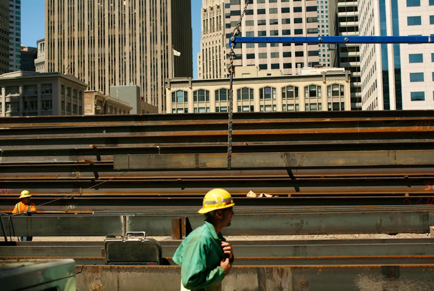 Workers guide steel beams into place at a construction site in San Francisco, California September 1, 2011.