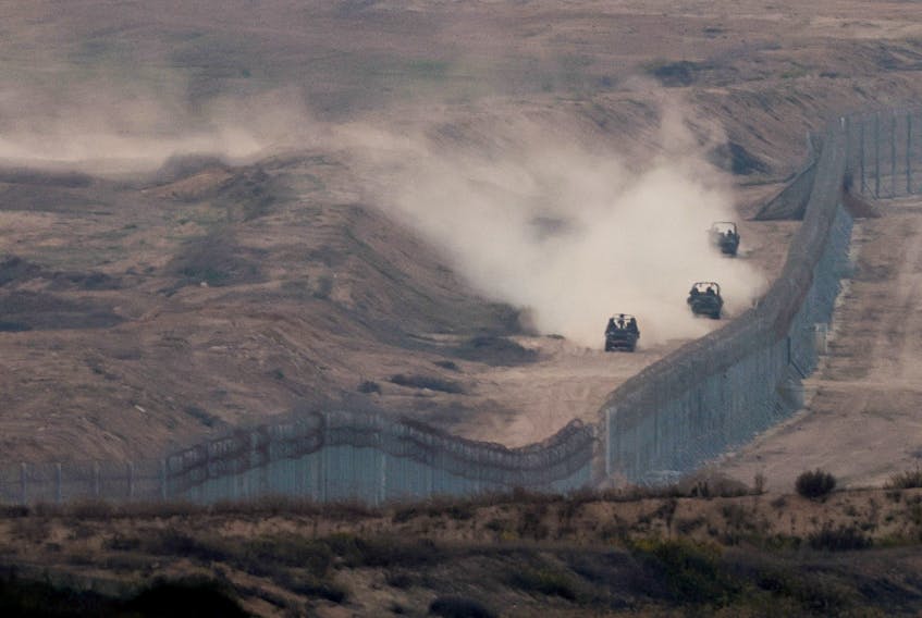 Military vehicles manoeuvre next to a fence, as seen from the Israeli side of the border with Gaza, November 5, 2023.