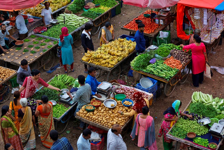 Customers buy fruits and vegetables at an open air evening market in Ahmedabad, India, August 21, 2023.