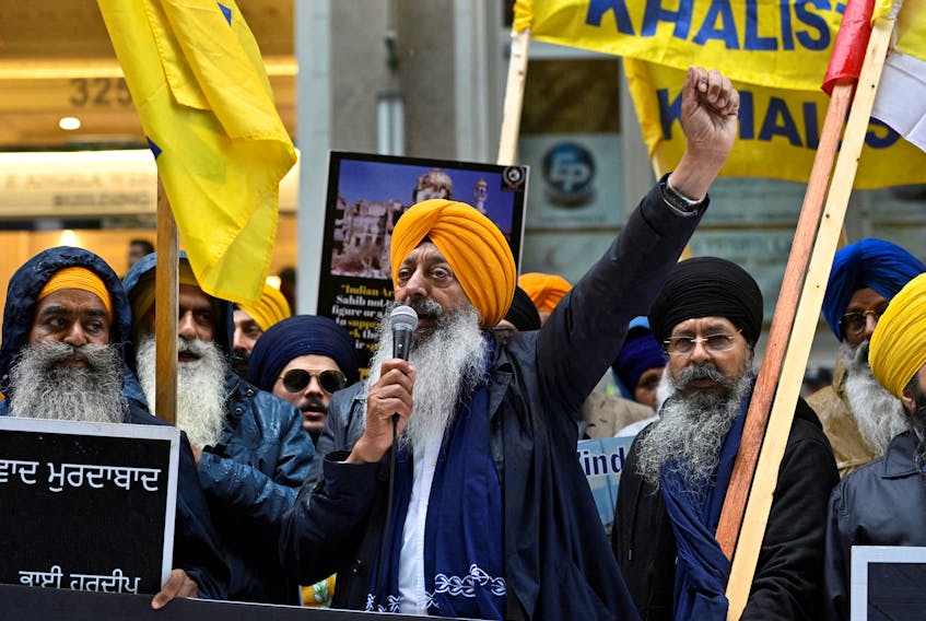 A demonstrator uses a microphone as others hold flags and signs as they protest outside India's consulate, a week after Canada's Prime Minister Justin Trudeau raised the prospect of New Delhi's involvement in the murder of Sikh separatist leader Hardeep Singh Nijjar, in Vancouver, British Columbia, Canada September 25, 2023. 