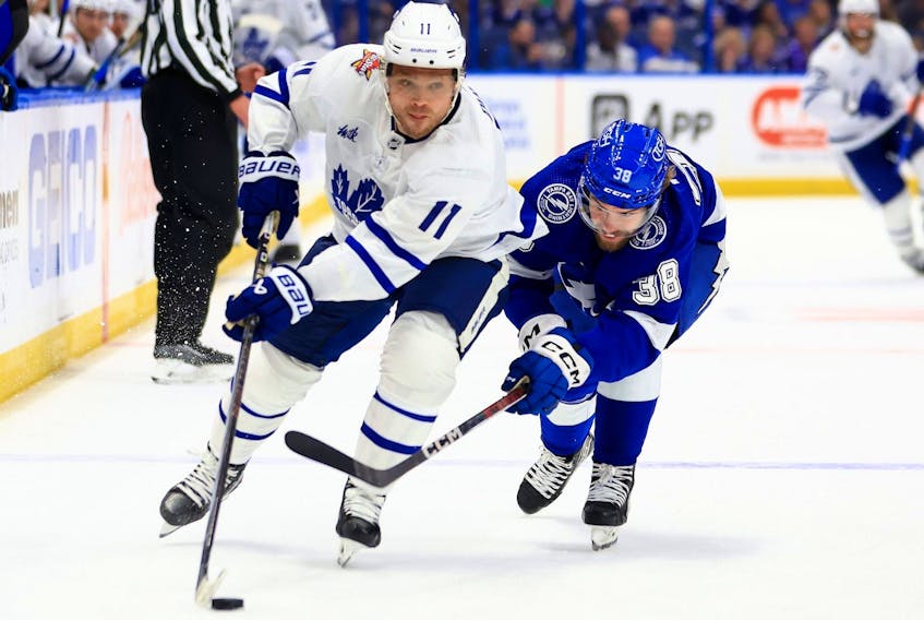 Max Domi (11) of the Toronto Maple Leafs and Brandon Hagel (38) of the Tampa Bay Lightning fight for the puck in the third period during a game  at Amalie Arena on Oct. 21, 2023, in Tampa, Fla.