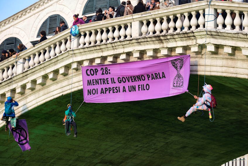 People hang a banner over Grand Canal during a protest by 'Extinction Rebellion' climate activists in Venice, Italy, December 9, 2023.