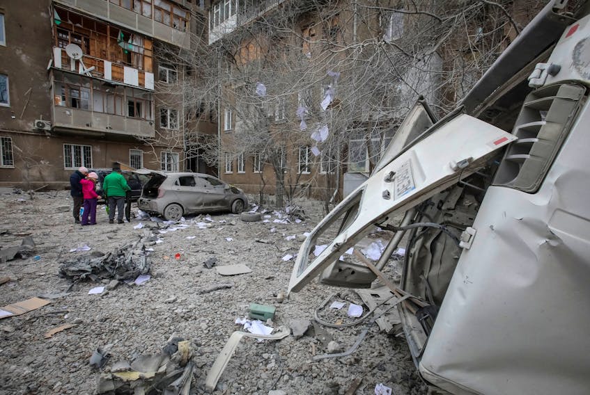 Local residents stand near their apartment building and cars damaged during a Russian missile strike, amid Russia's attack on Ukraine, in Kharkiv, Ukraine December 8, 2023.