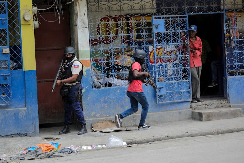 A man looks out of a store as police patrol the streets after gang members tried to attack a police station, in Port-au-Prince, Haiti April 25, 2023.