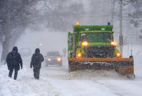 A City of St. John’s snowplow passes pedestrians on Lemarchant Road Tuesday morning, Feb. 14.