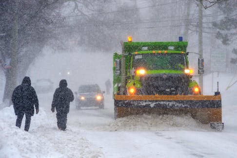 A City of St. John’s snowplow passes pedestrians on Lemarchant Road Tuesday morning, Feb. 14.