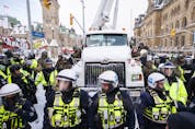 Police hang off a truck as authorities work to end a protest against COVID-19 measures that had grown into a broader anti-government demonstration and occupation lasting for weeks, in Ottawa, Saturday, Feb. 19, 2022.