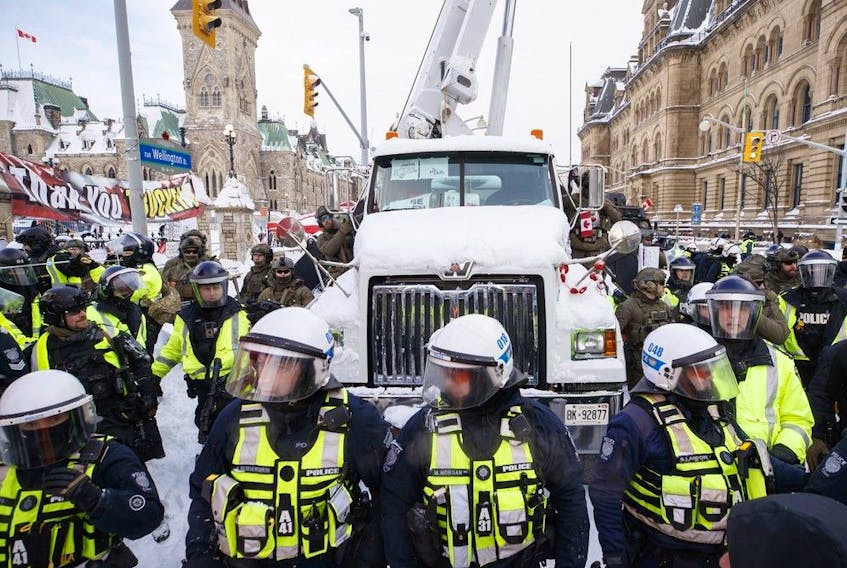 Police hang off a truck as authorities work to end a protest against COVID-19 measures that had grown into a broader anti-government demonstration and occupation lasting for weeks, in Ottawa, Saturday, Feb. 19, 2022.
