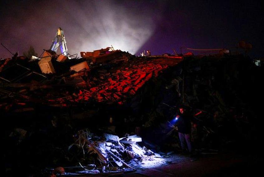  A man uses a flashlight to check damaged buildings, in the aftermath of an earthquake, in Antakya, Turkey, Feb. 8, 2023.