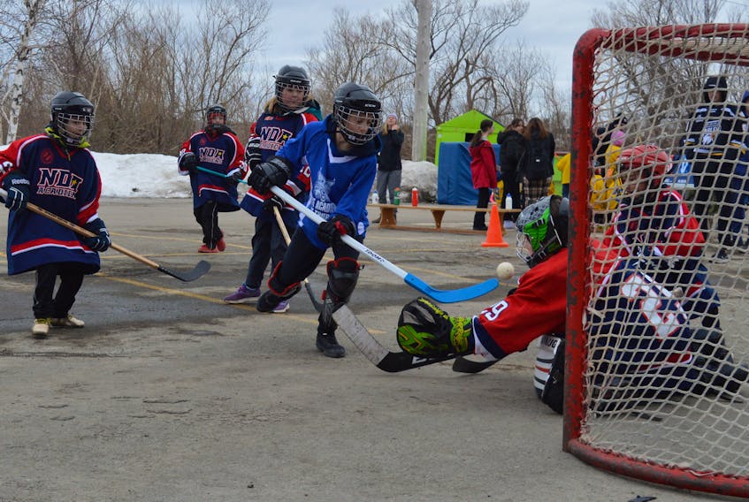 Ethan Wood, centre, of Ecole acadienne de Pomquet in Truro, fires a shot on NDA goaltender Sam Poirier during road hockey play at Centre Scolaire Étoile de l’Acadie in Sydney on Wednesday morning. The school was playing host to 400 children from across the province for floor hockey, ball hockey and other activities as part of their winter carnival festivities. For more coverage, see page A6. GREG MCNEIL/CAPE BRETON POST