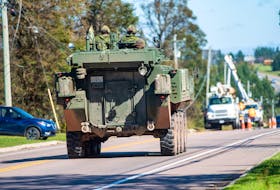 A Canadian army vehicle drives past a line crew from Ontario in Marshfield Sept. 29 as work continued on repairing downed lines caused by post-tropical storm Fiona. Brian McInnis • Special to The Guardian