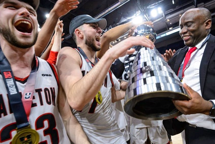 Halifax, Nova Scotia - Mar 12, 2023:  USports Men's Final 8 National Basketball Gold Medal Championship game between Carleton Ravens and St FX XMen at the Scotiabank Center in Halifax, Nova Scotia. From left, Connor Vreeken, Gebrael Samaha and coach Taffe Charles celebrate after the double-overtime win.