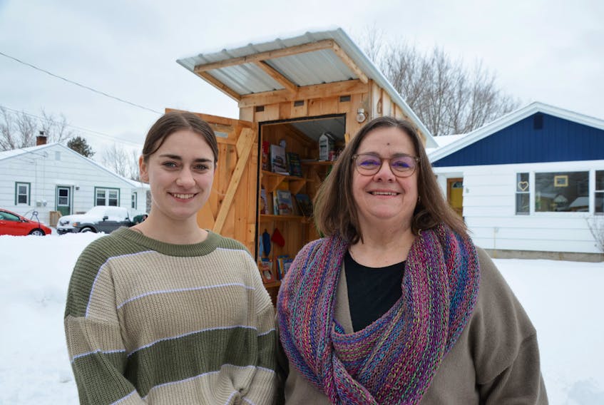 Mairéad MacInnis, left, and her mother Maureen MacInnis in front of the Community Pantry and Free Little Library in Lawrencetown. The two are among the many people who keep the tiny food bank stocked. 
Lawrence Powell